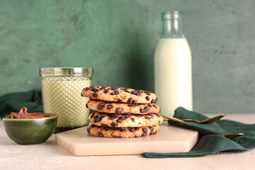 Cookies with milk, chocolate cream and spoons on white grunge table near green wall