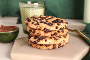 Cookies with milk, chocolate cream and spoons on white grunge table near green wall