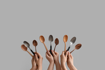 Female hands holding different spoons on grey background