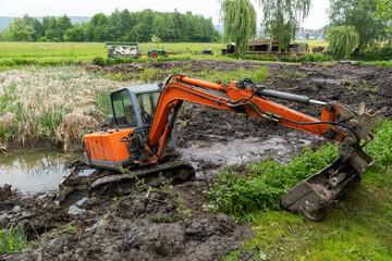 An excavator clears a silted lake