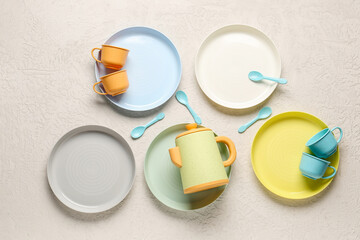 Plates with cups, teapot and spoons for baby on grunge white background