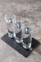 Glasses of vodka on grey background