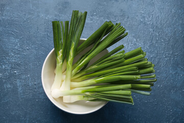 Bowl with fresh green onion on blue background