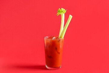 Glass of bloody mary with celery on red background