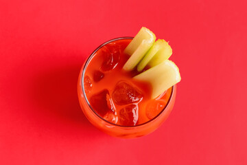 Glass of bloody mary with celery on red background © Pixel-Shot