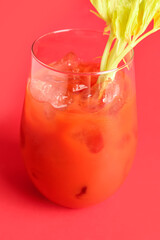 Glass of bloody mary with celery on red background