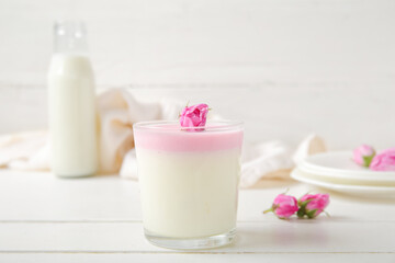 Obraz na płótnie Canvas Glass panna cotta with beautiful pink rose flowers on white wooden table