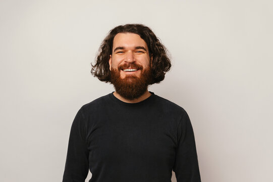Studio portrait of a handsome smiling confident bearded hipster man in black.