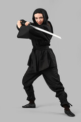 Female ninja with sword on grey background © Pixel-Shot