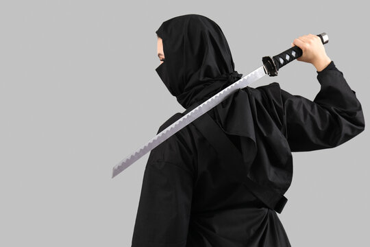 Female ninja with sword on grey background