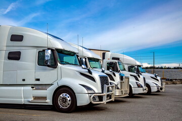 A row of white trucks in a construction machinery yard in an industrial area