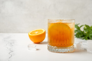 Glass of ice tea with orange and mint on white background