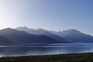 Early morning mist at Pangong Lake, Ladakh, creates a serene scene by the shore.