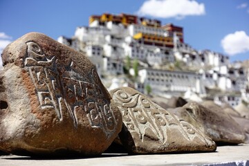 Mani stones with Tibetan Buddhist scripts, reminiscent of Lhasa's Potala Palace, grace the...