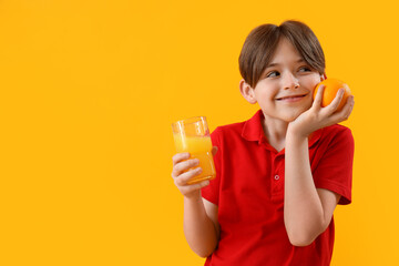 Little boy with orange and glass of juice on color background