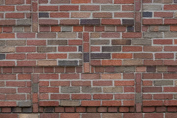 artisanal brick wall, in multi-color shades of red, brown, beige and gray, American or common bond pattern uses header half bricks every sixth row, with a decorative vertical row of half-bricks