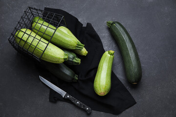 Basket with fresh green zucchini on black background