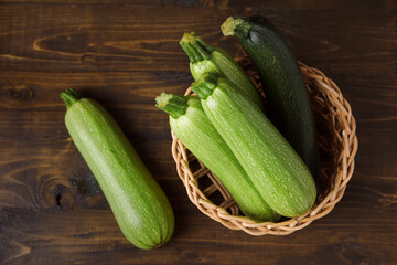 Wicker bowl with fresh green zucchini on wooden background