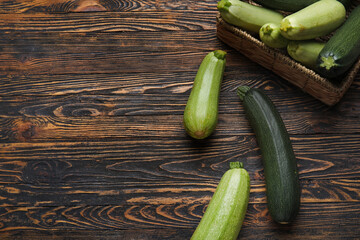 Wicker box with fresh green zucchini on wooden background