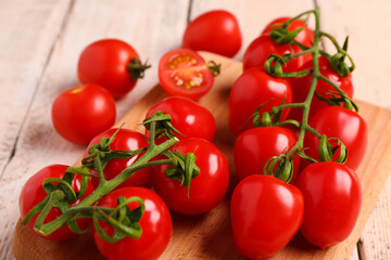 Board with fresh cherry tomatoes on white wooden background