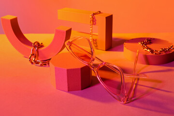 Podiums with stylish sunglasses and chain bracelets on orange background
