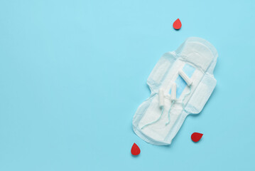Composition with menstrual pad. tampons and blood drops made of paper on blue background