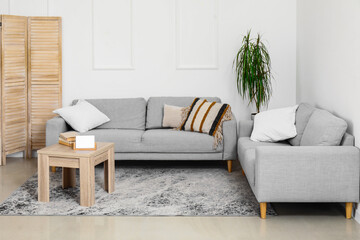 Interior of living room with cozy grey sofas and wooden coffee table