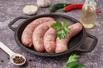 Frying pan with raw homemade sausages on grunge background