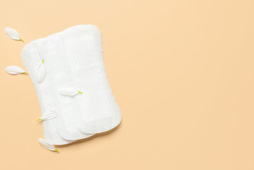Menstrual pads and chamomile petals on beige background