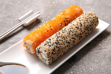 Plate with sushi rolls on grey background