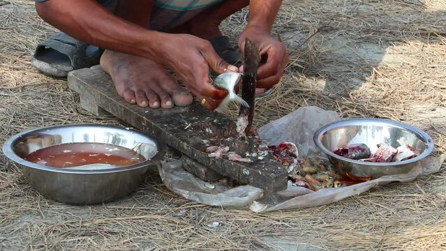 A male worker cuts fish with a traditional fish cutter.
