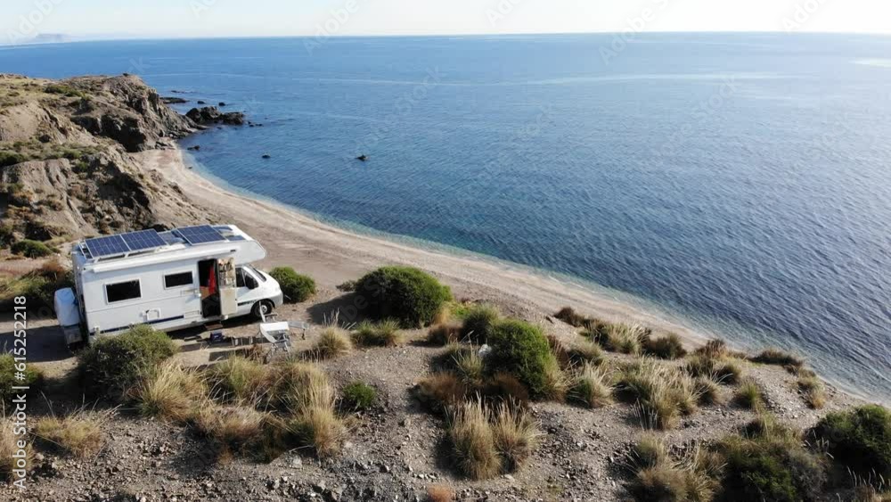 Wall mural aerial view. camper rv with solar photovoltaic panels on roof camping on cliff sea shore in winterti