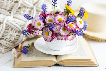 Obraz na płótnie Canvas Congratulations for Mother's or Women's day, birthday or anniversary. Countryside decor, old book, wooden background, straw hat. Greeting postcard with bright summer or spring flowers in a cute cup