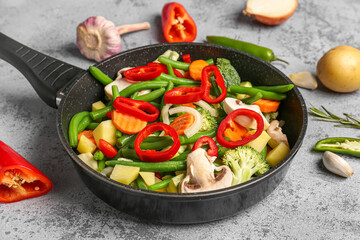 Frying pan with fresh vegetables on grey background - obrazy, fototapety, plakaty