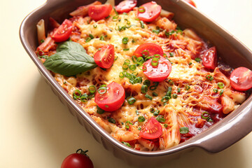 Baking dish of pasta with tomato sauce and cheese on beige background