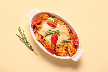 Baking dish of pasta with tomato sauce and cheese on beige background