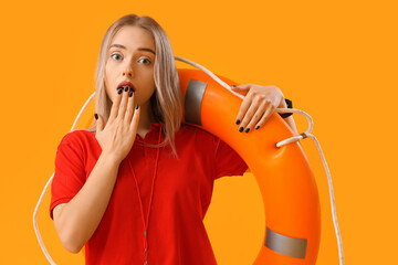 Shocked female lifeguard with ring buoy on yellow background