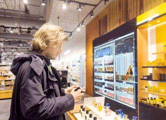 Fototapeta premium buying make up at cosmetics section in store. choosing cosmetics, perfumes, creams and shampoos, Using tester.
