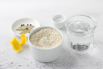 Ingredients: long grain rice, water, salt, spices for making delicious steamed rice on a light blue background