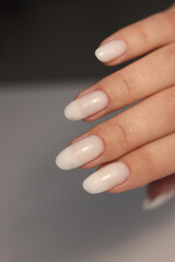 Nude manicure. Long almond shaped nails. Nail design. Manicure with gel polish. Close-up of the hands of a young woman with a gentle nude manicure on the nails. Bright nails with gel polish.