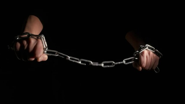 Violence move with chain on black background. A view of hands hold with stressed emotions the metal chain against black background.