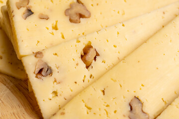 Sliced piece of milk cheese with walnuts