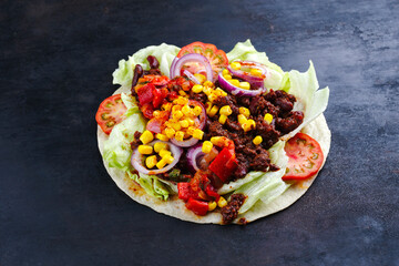 Traditional Mexican tortillas with vegetable, kidney beans and lettuce served as close-up on a...