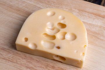 A cut piece of ripe cheese with lots of holes