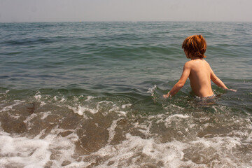 niño pelirrojo bañándose en la playa en verano