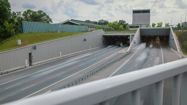 Time-lapse Shot Car Traffic City Road Tunnel Highway. Long Exposure Speedway In Warsaw City, Poland. Lot Of Cars Driving Fast Busy Modern Roadway. Daylight Sunny Summer Weather Rush Hour Timelapse