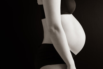 Side view of naked round belly of pregnant woman in underwear during last pregnancy month. Last...