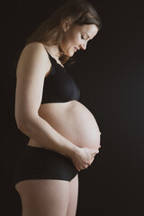 Side view pregnant woman in underwear and her naked round belly during last pregnancy month. Last...