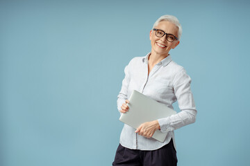 Confident smiling businesswoman holding laptop computer, looking at camera