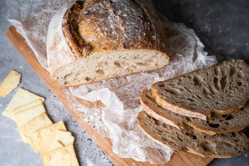 Sliced loaf of bread on a cutting board and crackers, top view
